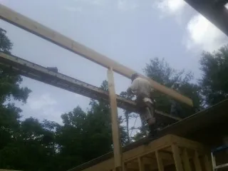 Carpenter setting a ridge beam over a new addition frame — Ice Dam Removal by Roofing Brothers in Neotsu