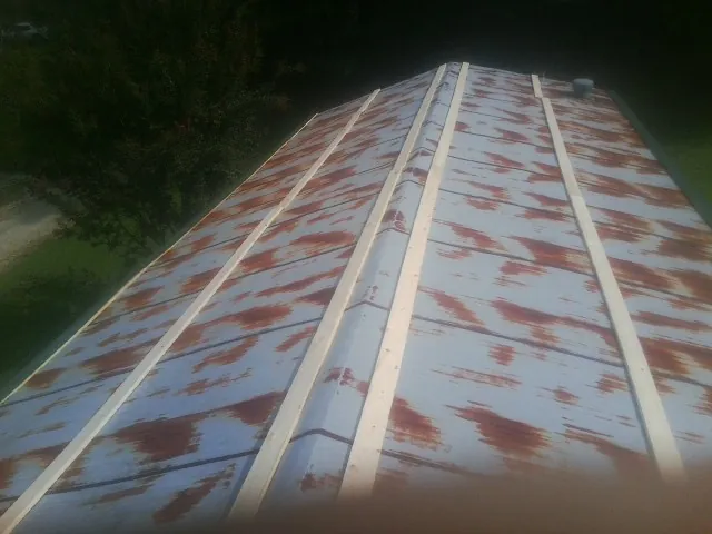 Rusted metal roof panels with new wood purlins before replacement — Storm Damage Roof Repair in Neotsu by Roofing Brothers