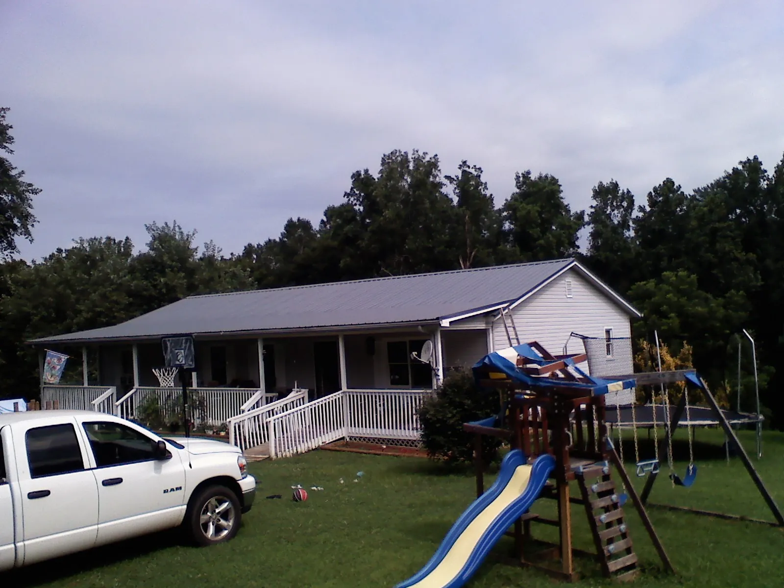 Dark metal roof on a country home with a full length front porch in Neotsu