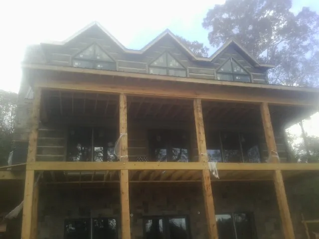 Dormers and porch framing on a large log home under construction — Roof Coating work by our crew in Neotsu