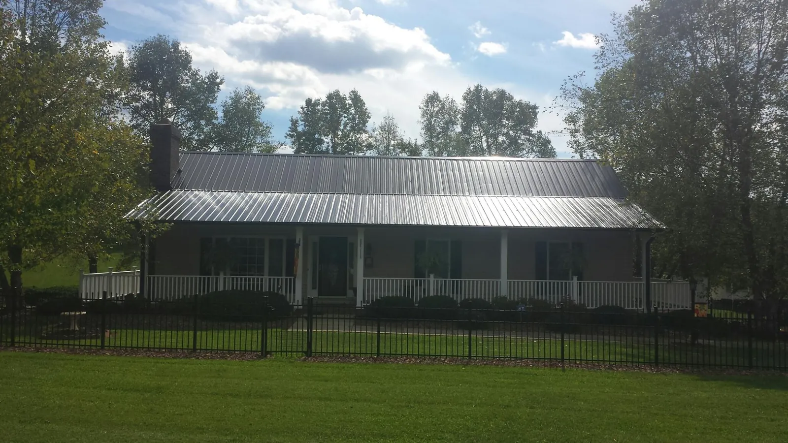 Gray metal roof on a brick ranch with a full width front porch — Gutter Guard Installation work by our crew in Neotsu