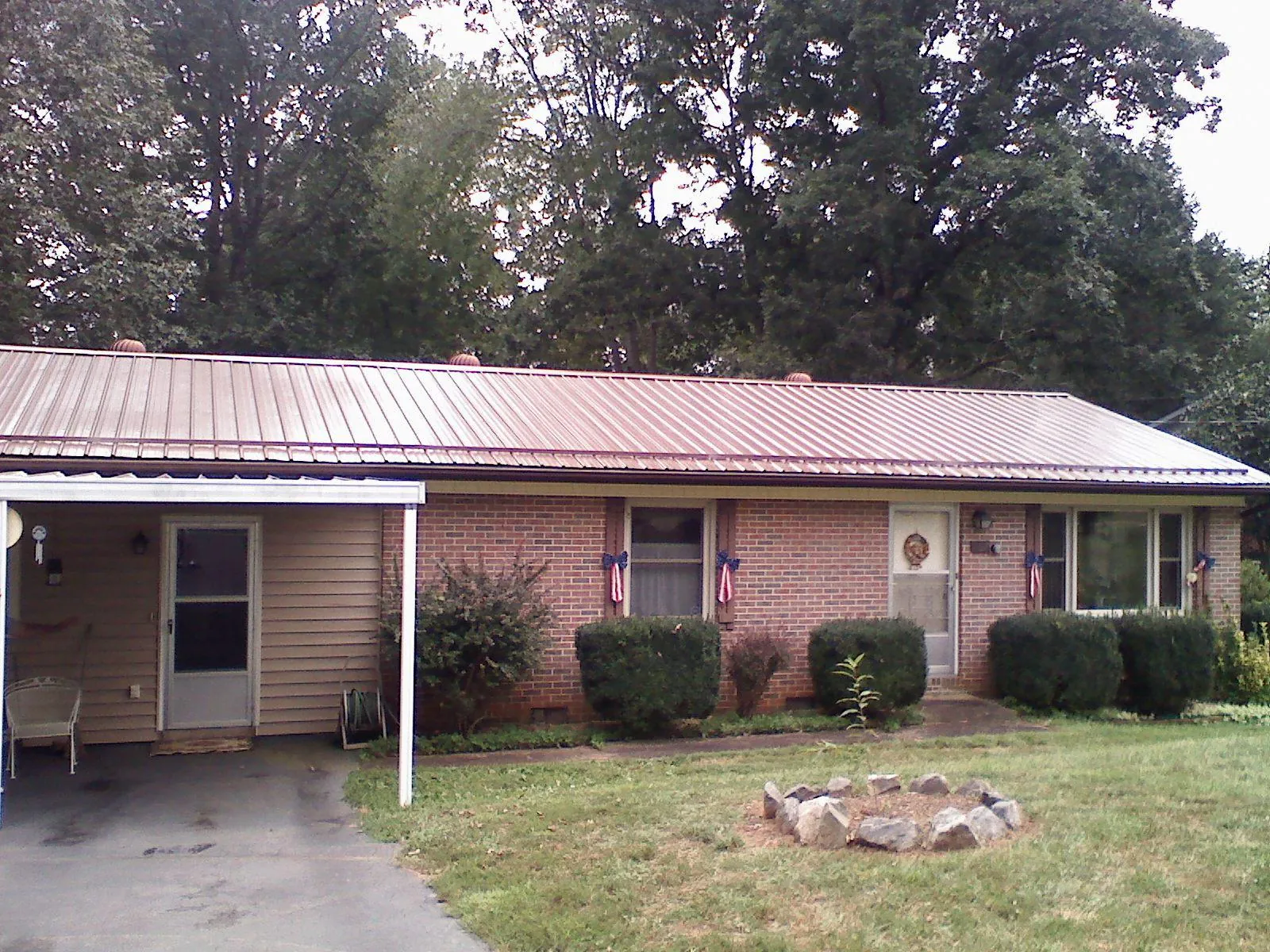 Bronze metal roof and carport on a brick ranch home — Roof Repair work by our crew in Neotsu