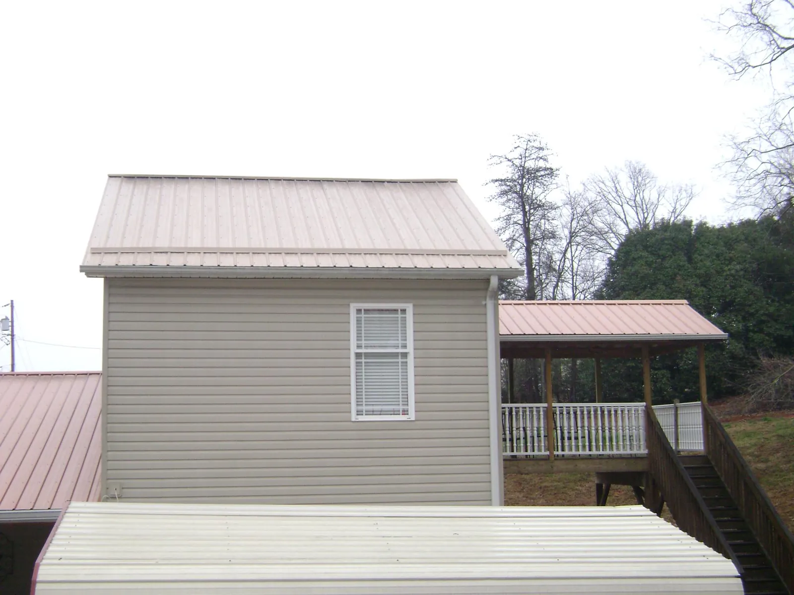 Tan metal roofs on a two story addition and attached porch, from a Roof Replacement job in Neotsu